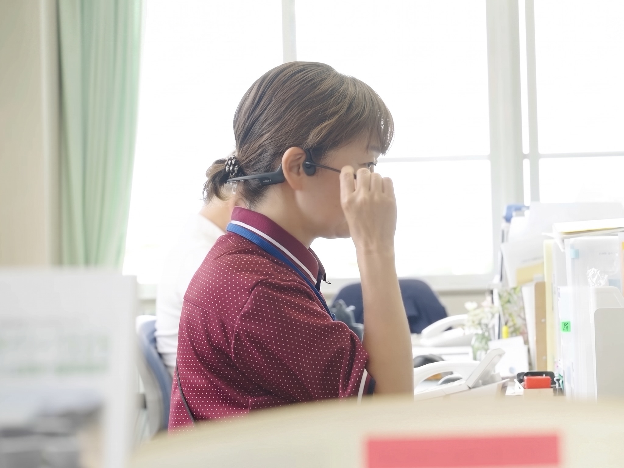 あさひホーム 事務所のデスクでBONX WORKを活用しグループトークを行う女性職員のイメージ