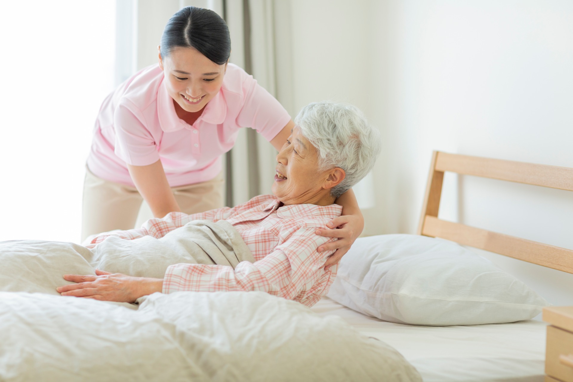 起き上がり介助する女性介護スタッフ　イメージ