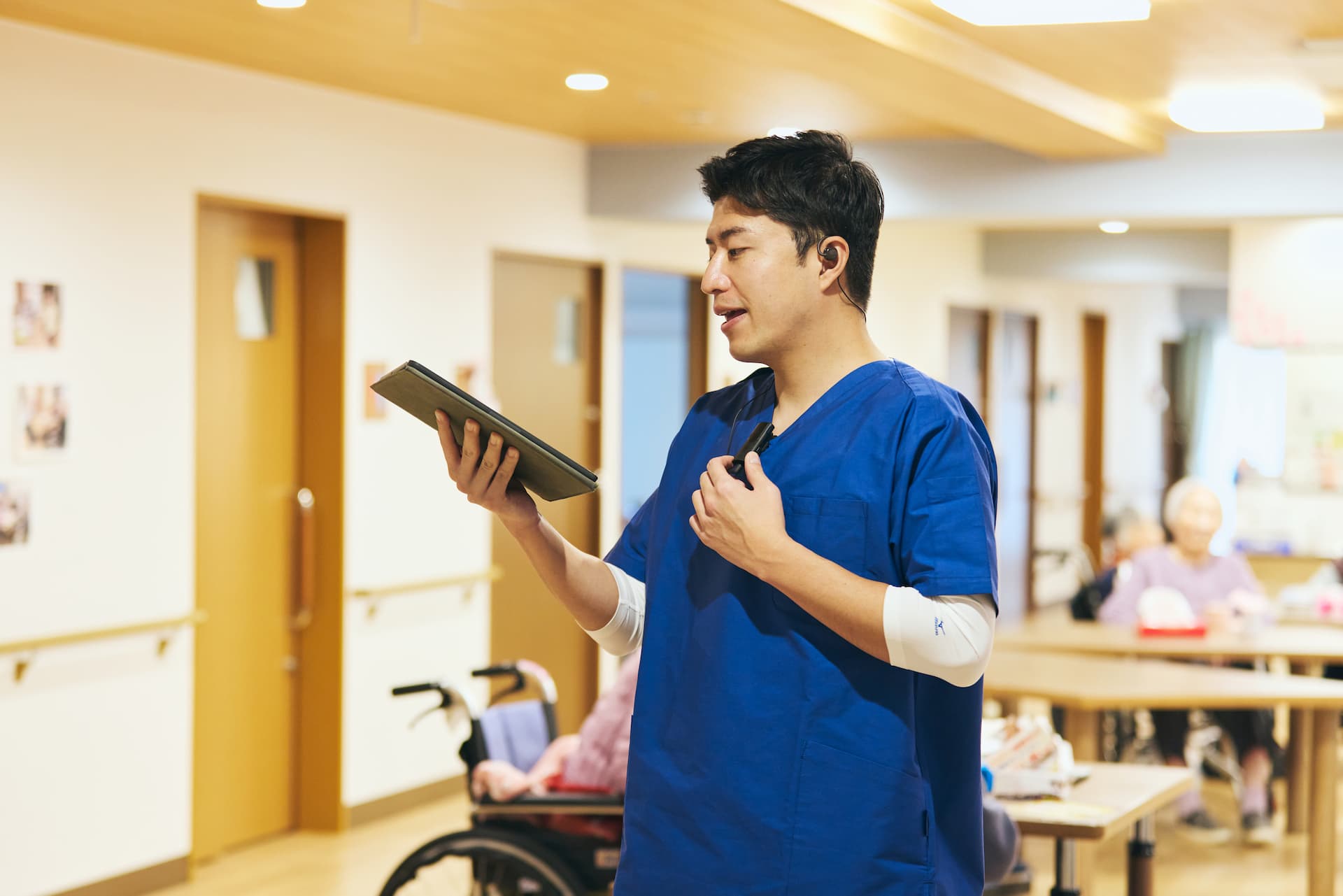 iPadの介護記録を確認しながらスマホインカムで通信を行う介護の男性職員