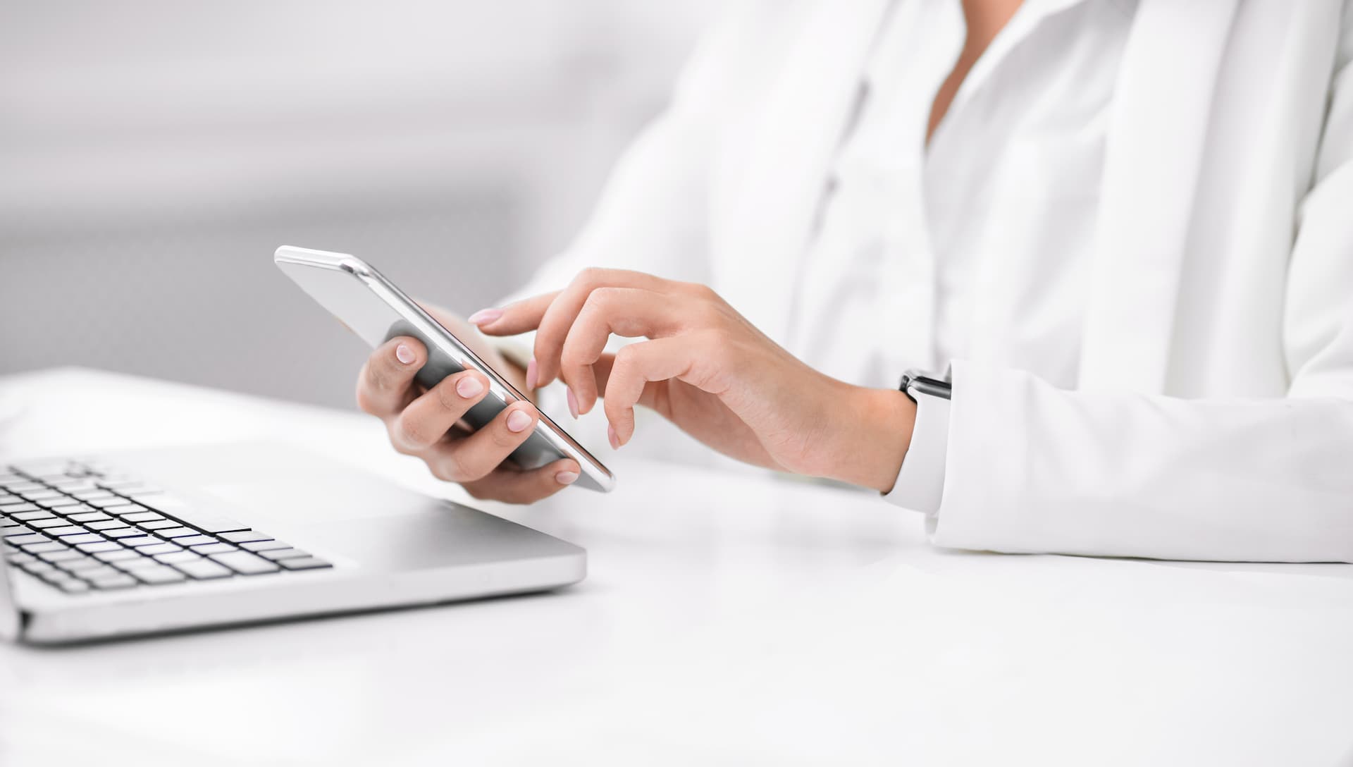 スマホを操作する白衣を着た女性のイメージ